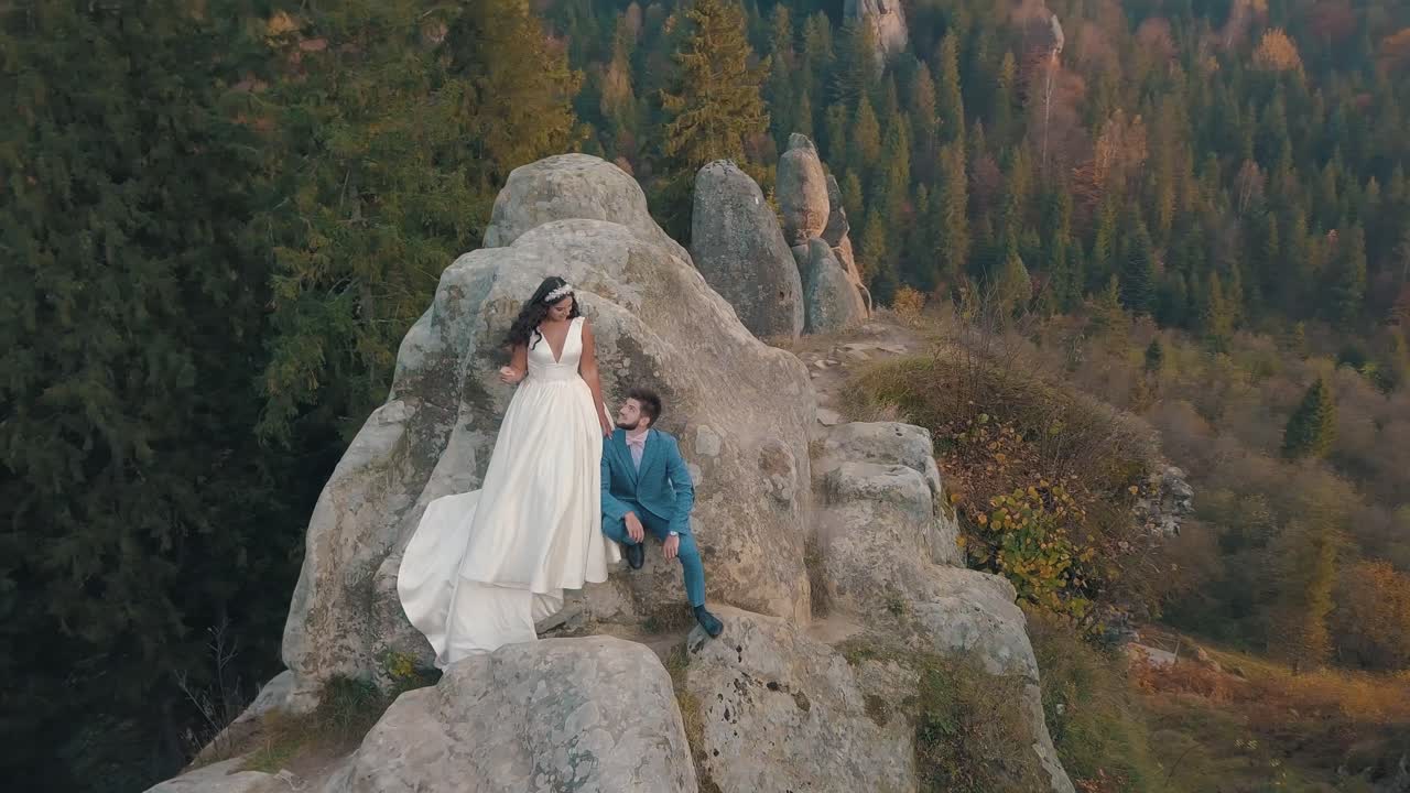 los recién casados están en una ladera alta de la montaña. el novio y la novia.