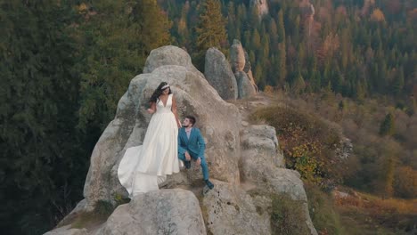 Newlyweds-stand-on-a-high-slope-of-the-mountain.-Groom-and-bride.-Arial-view