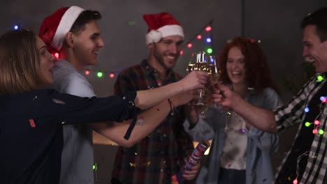 Gruppe-Von-Freunden,-Die-Feiern-Und-Die-Silvesterparty-Genießen-Und-Spaß-Haben.-Freundlich-Und-Fröhlich.-Glückliches-Gefühl.-Weihnachtsdekorationen-Zu-Hause.-Mann-Explodiert-Mit-Konfettistangen-Und-Klirrt-Mit-Champagnergläsern