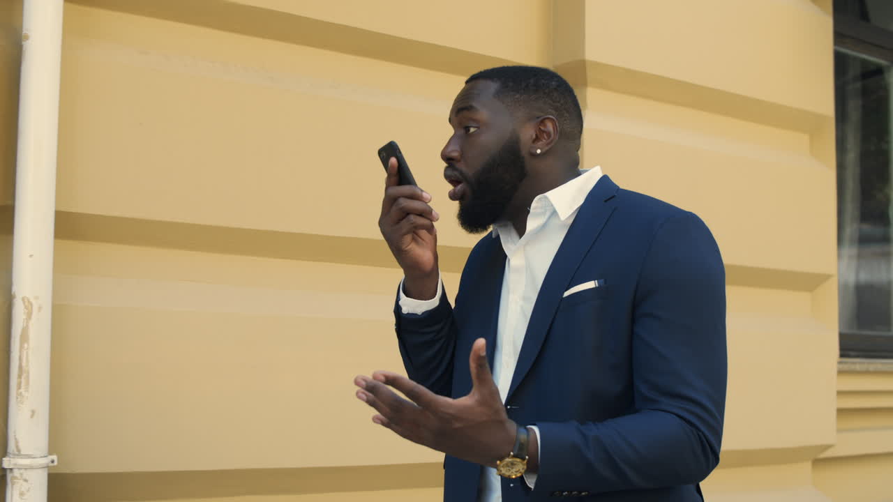 Busy businessman walking outdoors and talking on smartphone