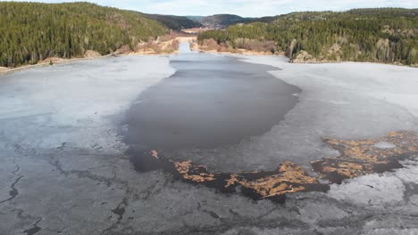 Aerial-Shot-Of-Driftwood-Frozen-In-Ice-On-A-Lake,-Beautiful-Spring-Landscape