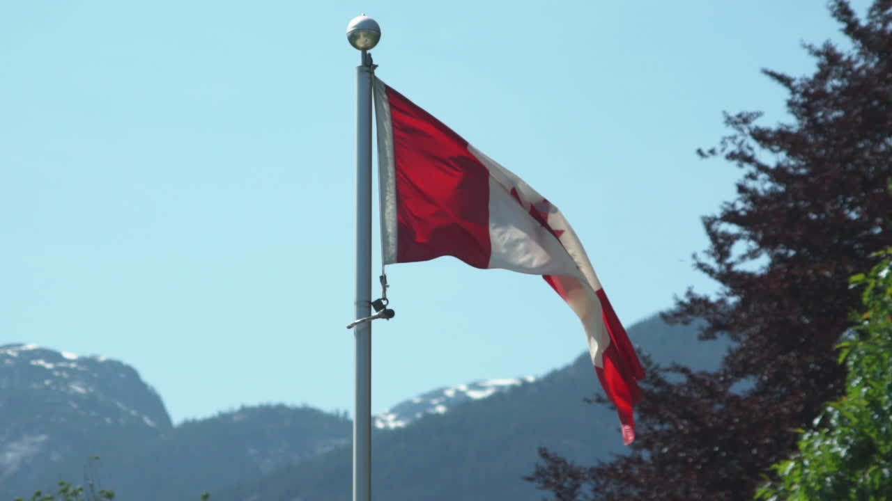 Kanadische Flagge im Wind mit Bergen im Hintergrund