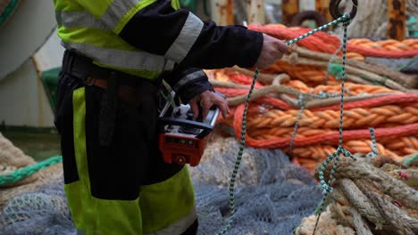 ship worker operating hoist machine lifting heavy ropes, close up