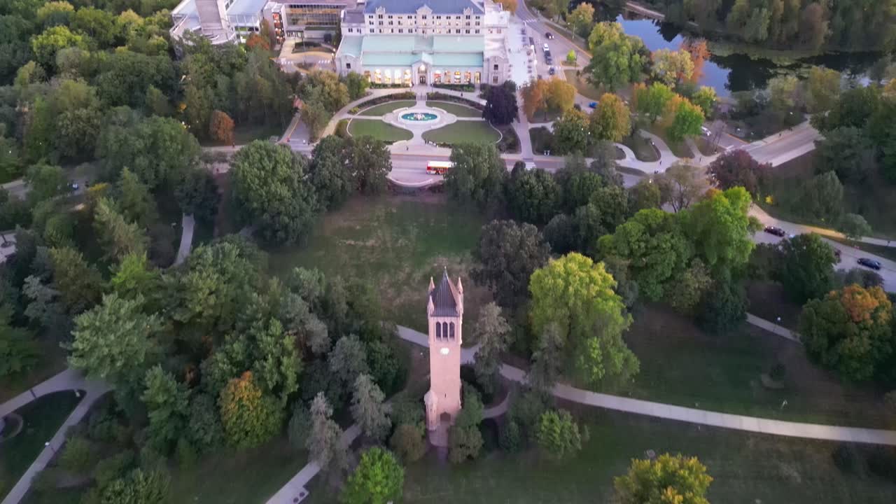 A drone shot of the iconic Iowa State Campanile, revealing the south side of campus bathed in warm sunset hues.