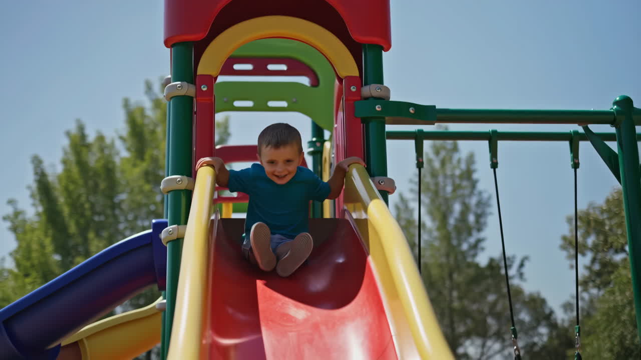 Happy Young Boy Sliding Down a Colorful Playground Slide