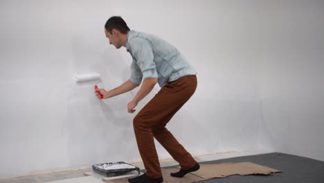 male decorator painting a wall with white color.