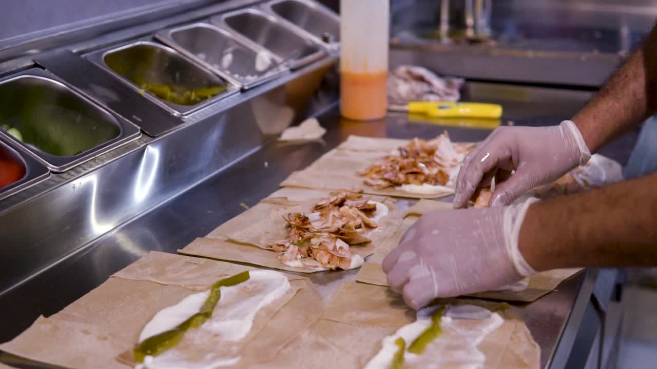 chef poniendo shawarma de pollo en pan pita en la cocina, disparo de cerca