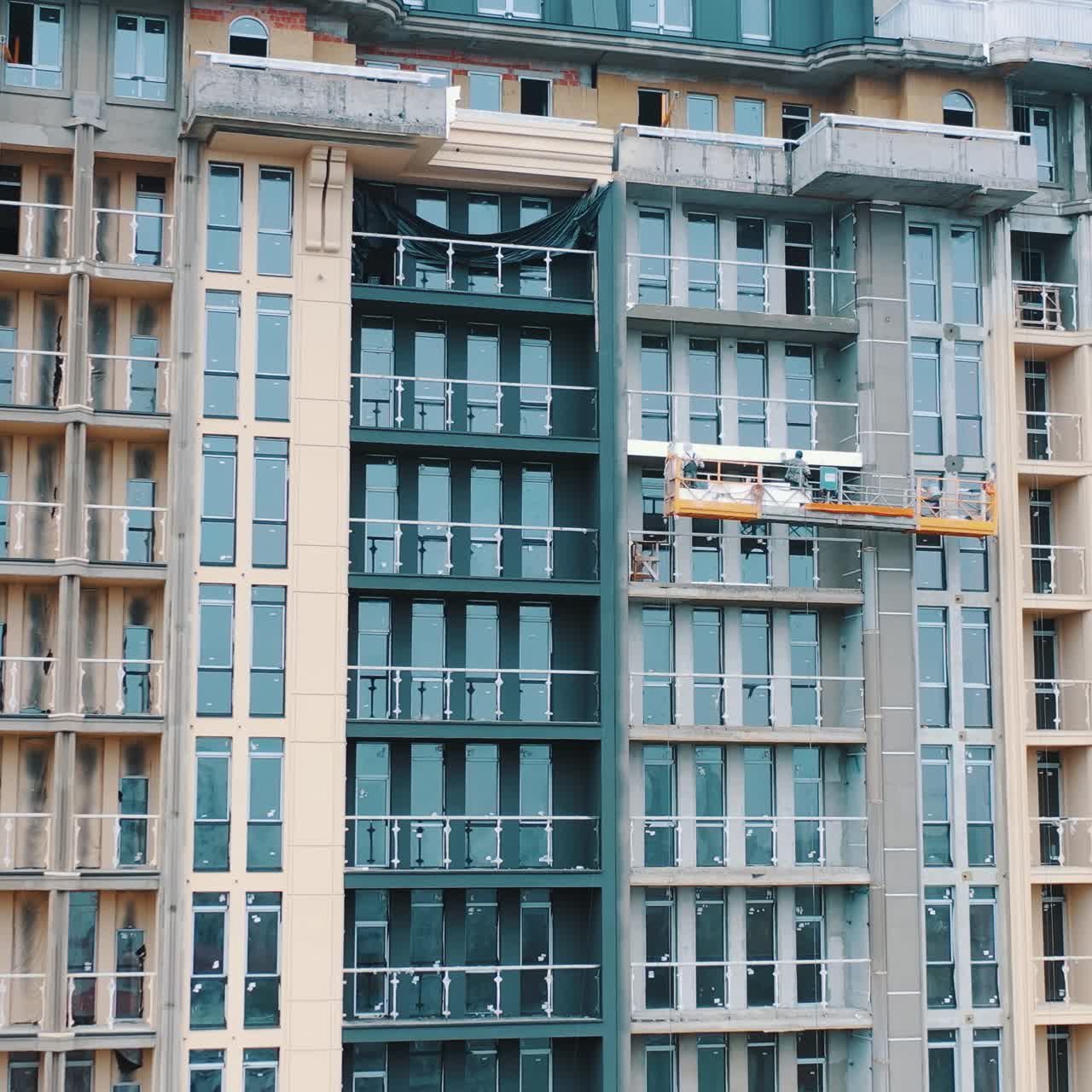 Construction of a modern building in the city. Facade of multistorey apartment house with plastic windows in the city. Building of a new architecture.