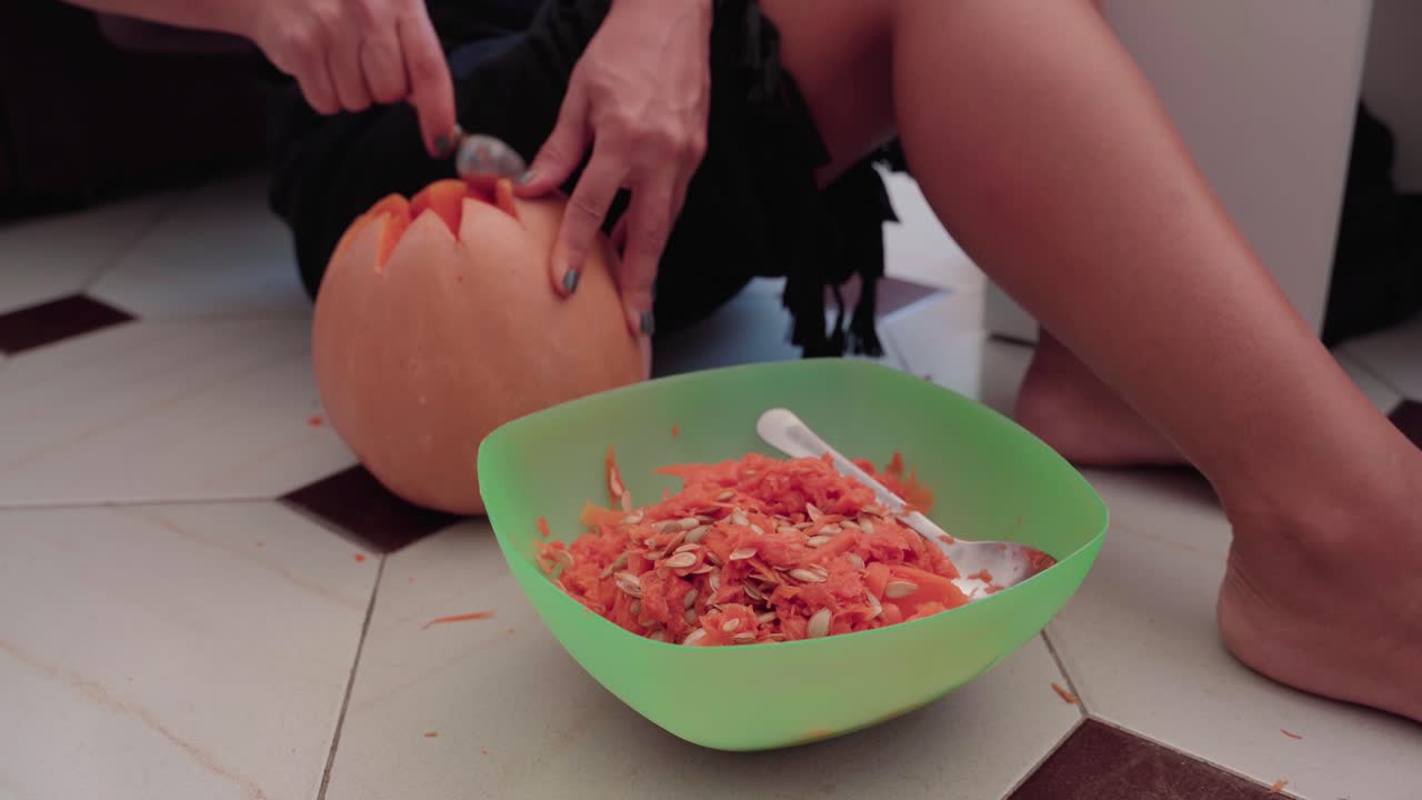 잭 오 랜턴을 조각하기 위해 호박 내부를 퍼내는 여자의 손을 닫습니다