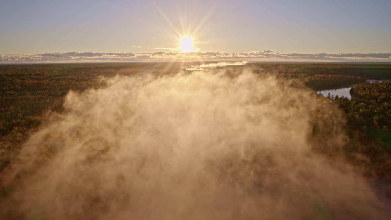 Cinematic sunrise drone shot with mist lifting over calm water