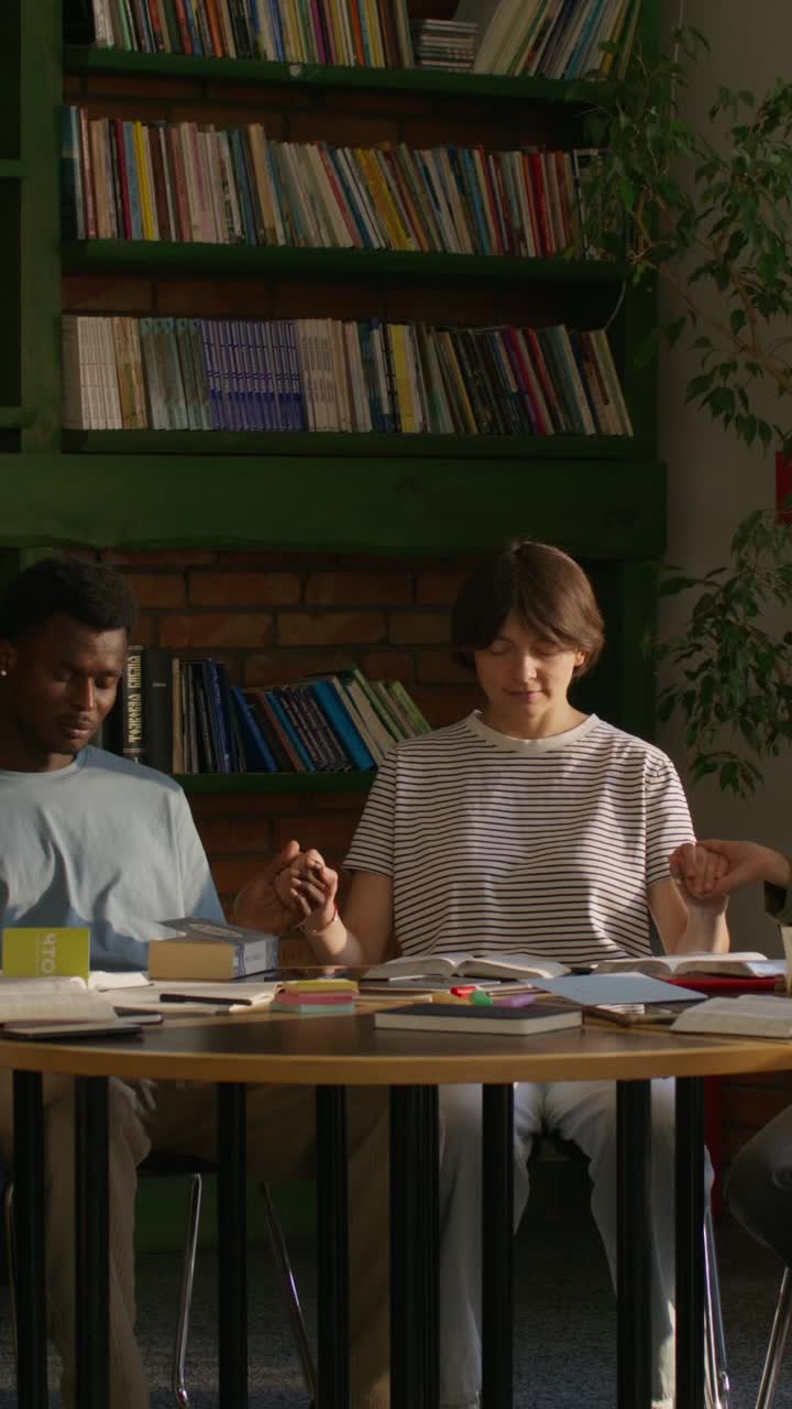 estudiantes orando juntos en una biblioteca