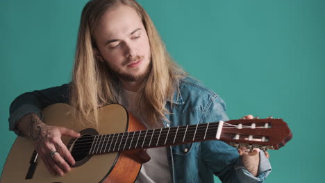 caucasian young man tuning the guitar on camera.