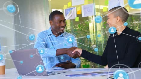 Animation-of-network-of-digital-icons-over-diverse-man-and-woman-shaking-hands-at-office