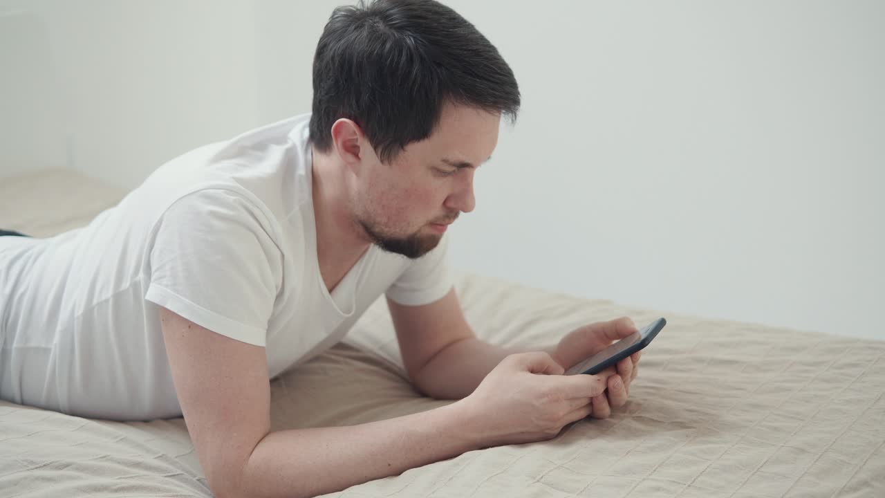 침대에서 스마트폰을 사용하는 남자