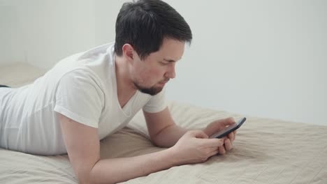 침대에서 스마트폰을 사용하는 남자