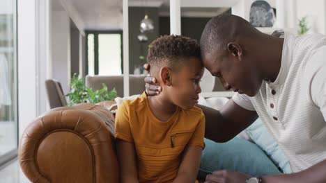 video of happy african american father and son hugging at home