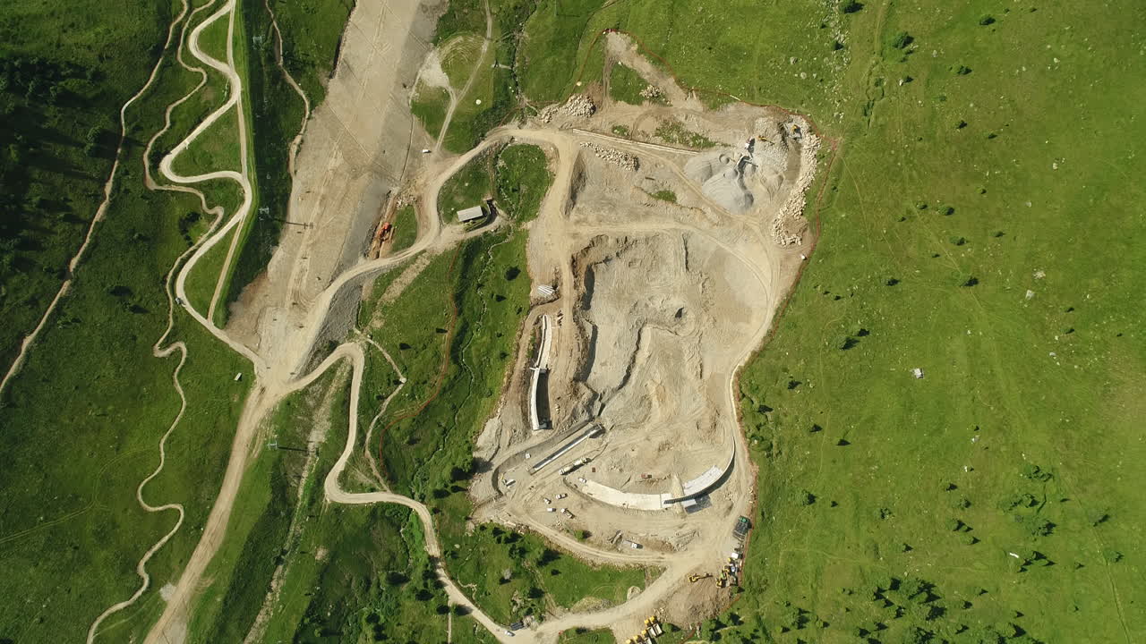 Top down aerial drone shot of a dam construction site in the alpine mountains