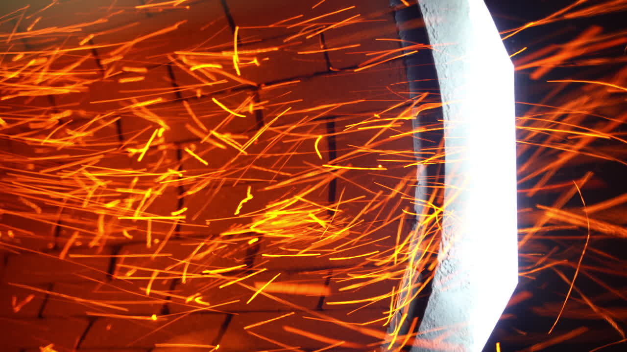 Little orange sparkles flying quickly from a stove pipe. Hot red particles at the backdrop of orange bricks. Close up.