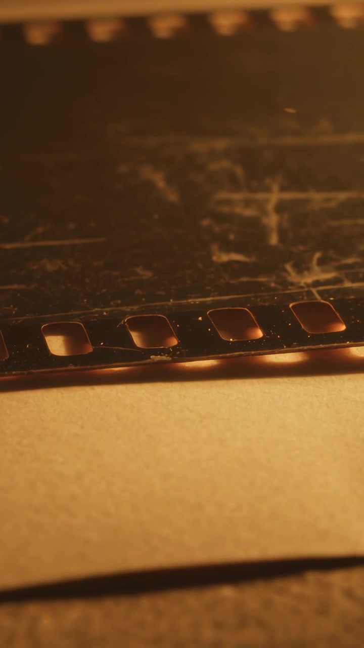 Vertical video: Racking camera revealing 35mm film perforations on paper for scanning