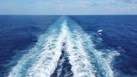 Sailing-boat-trails-in-beautiful-blue-water-at-the-ocean,-boat-flowing-and-leaving-white-swirl-trails-behind-during-sunshine-day