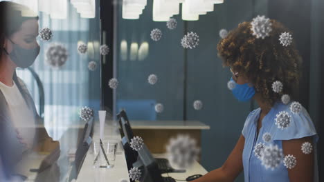 animation of covid-19 cells over caucasian woman wearing face mask paying her bill at hospital