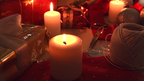 Cozy-christmas-background-with-candles,-gifts-and-wrapping-equipment