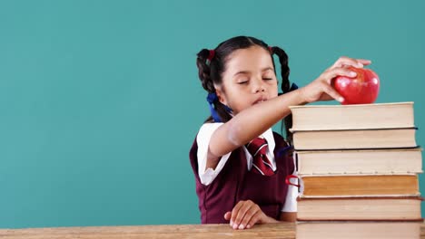 Schoolgirl-keeping-apple-on-stack-of-books