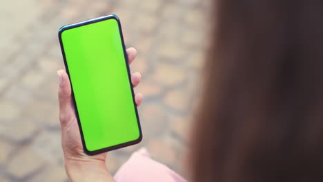 person holding a smartphone with a green screen display