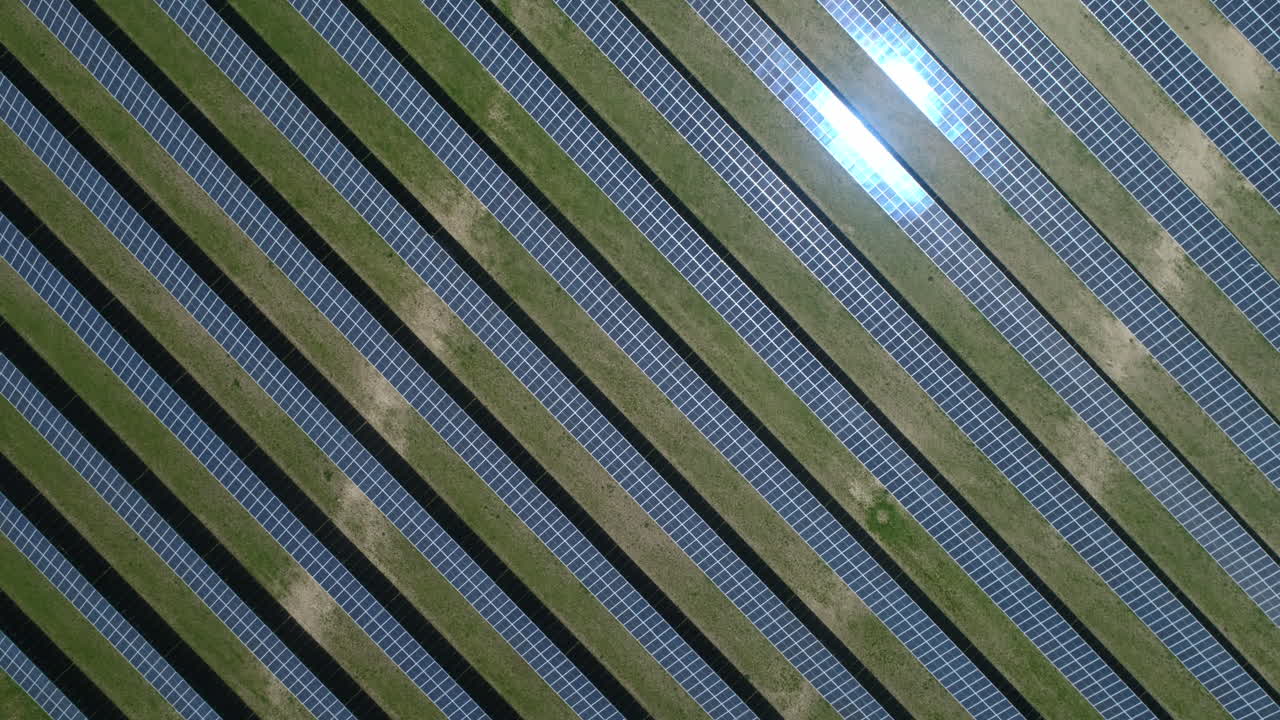 disparo de arriba hacia abajo sobre el campo de paneles solares en una granja solar con reflejo en el día soleado