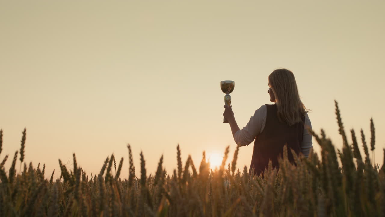 Contadina che solleva la coppa del campione in un campo di grano al tramonto.