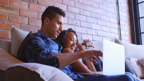 Couple-using-laptop-on-sofa-at-home-4k