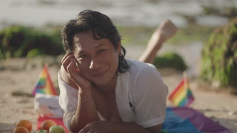 relaxed man at beach picnic with pride flag