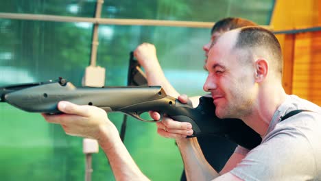 close-up young guys shoot at shooting range from pneumatic guns recharge cartridges