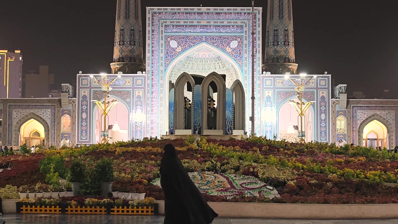 Woman in Abaya Walking Past Illuminated Mosque at Night