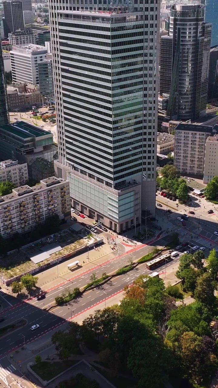 Vista aérea con dron del centro moderno de la ciudad de Varsovia con rascacielos, parques verdes y tráfico urbano durante un día soleado de verano en Polonia. Vídeo vertical