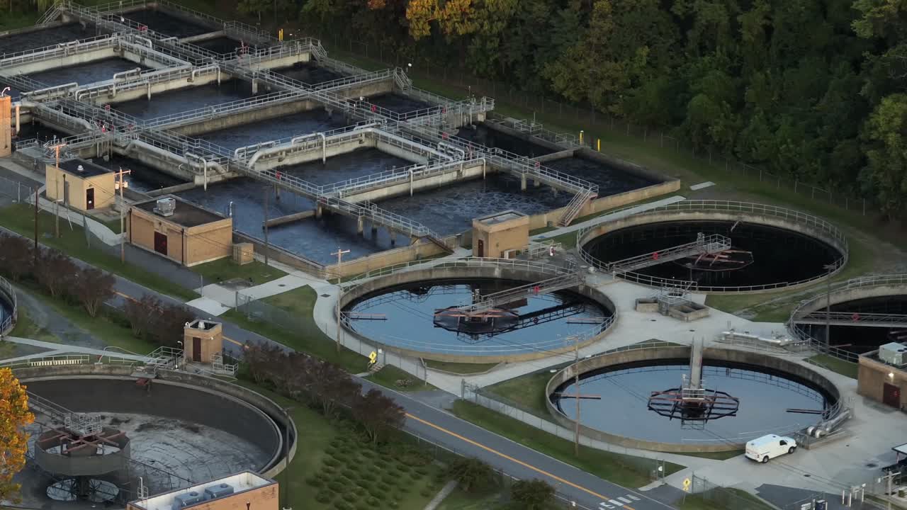 Aerial view of pools and pond of wastewater treatment plant in United States. Dusk scene in the evening. Water purification plant in USA. Wide shot