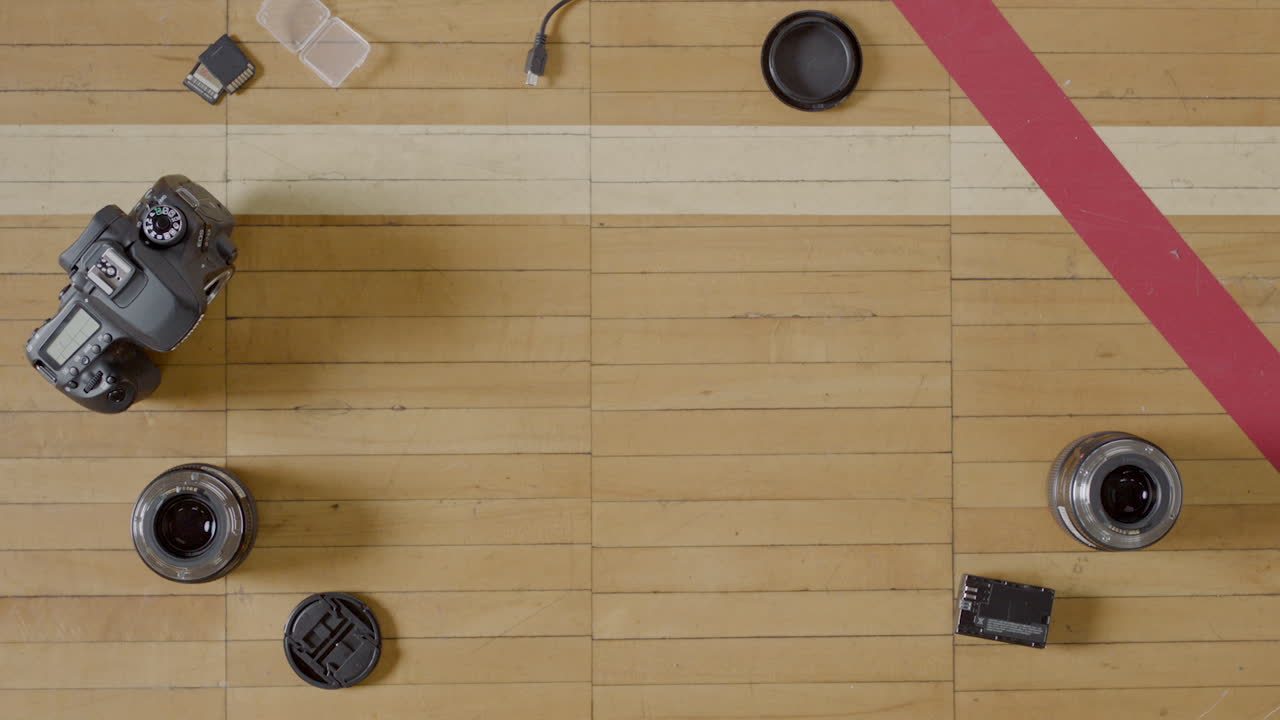 Overhead shot of camera equipment, DSLR equipment, on a wooden basketball court.