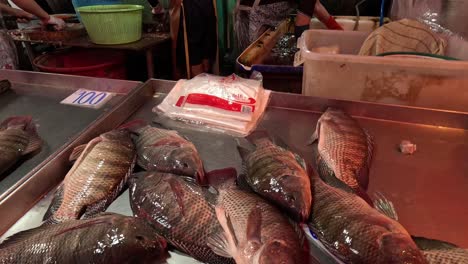 fresh fish on ice at a busy market stall