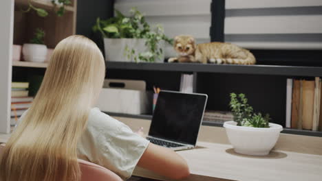 A-teenage-girl-does-homework,-a-cat-sits-on-the-windowsill-nearby