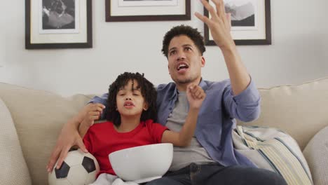 Happy-biracial-man-and-his-son-watching-football-match-together