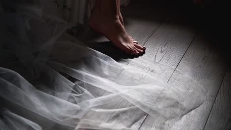 closeup footage of the lower part of a bride body sitting by the window wearing a dress and wedding veil