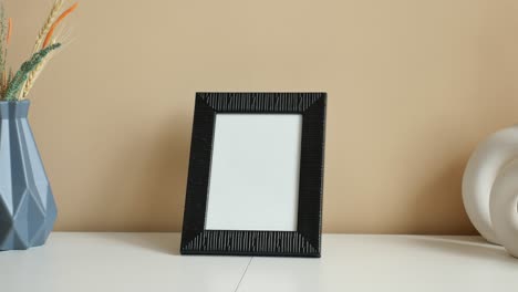 black picture frame with vases and dried flowers