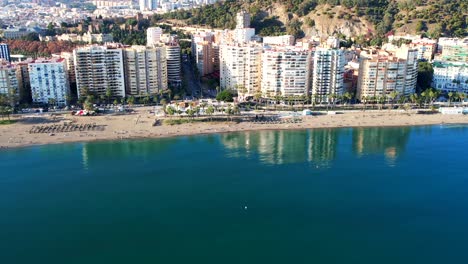 Vistas-A-La-Playa-Con-Un-Océano-En-Calma-Que-Refleja-Un-Hotel-Y-Apartamentos-De-Lujo-En-El-Agua