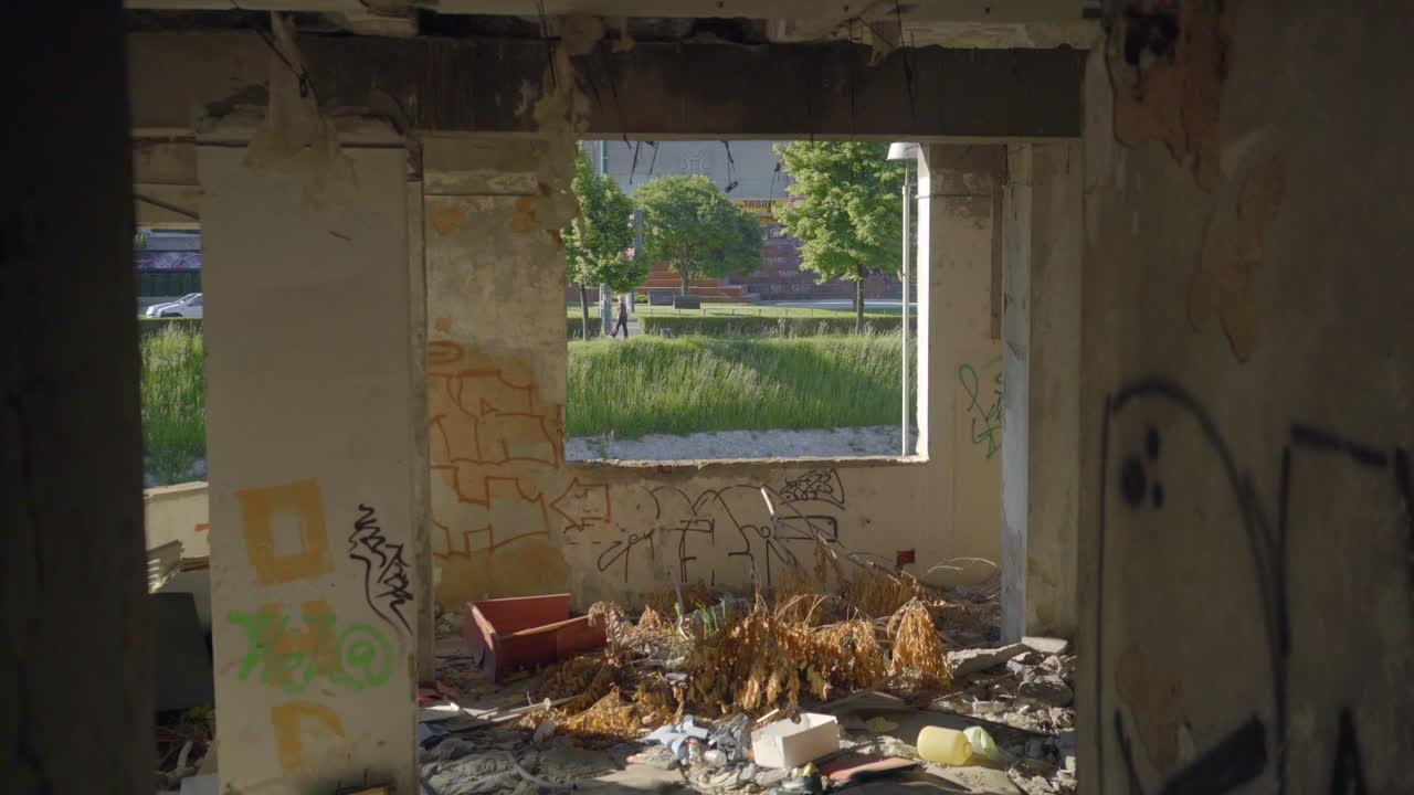Tilt down to Interior of abandoned building in Sarajevo, Bosnia. See through window to outside grass trees. Cinematic ruin and destruction.