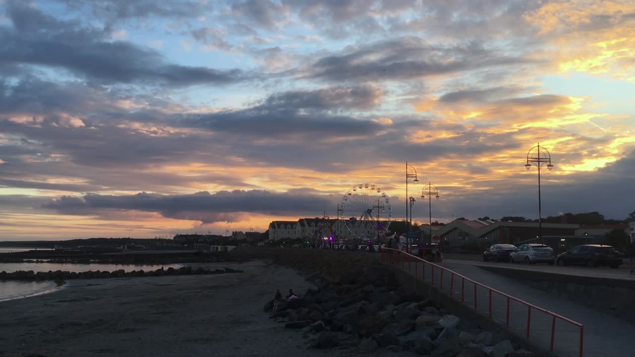 Sunset over a seaside promenade with a Ferris wheel
