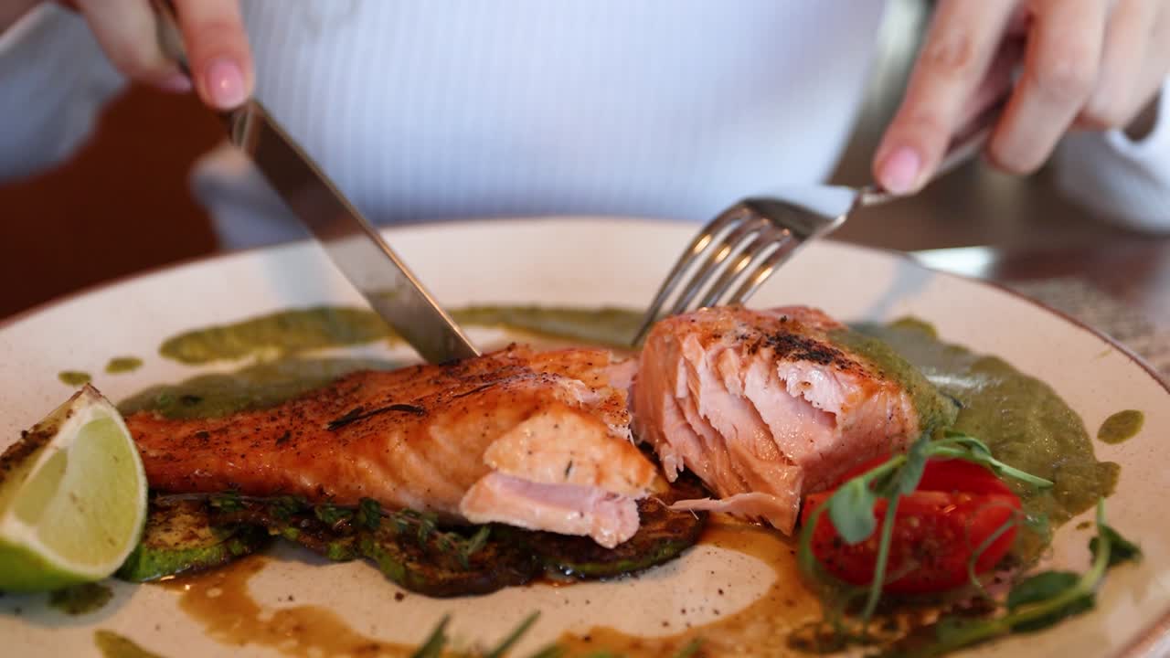 mujer comiendo salmón a la parrilla con verduras
