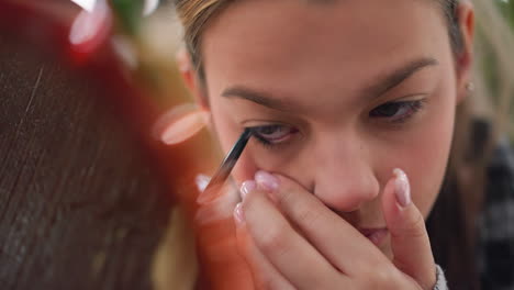 close-up shot of girl applying eye pencil to her eye, focus on precise makeup application technique, highlighting her hand movement and attention to detail in beauty routine