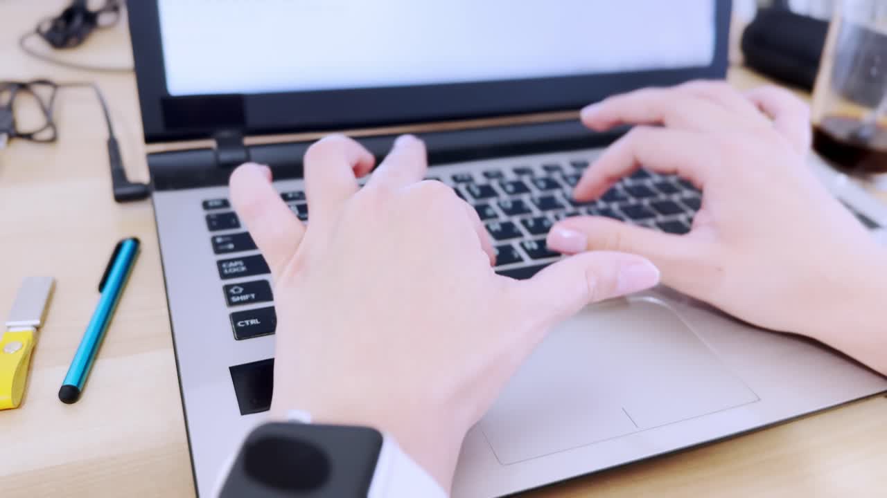 Detailed front close-up of a laptop keyboard with hands actively typing.