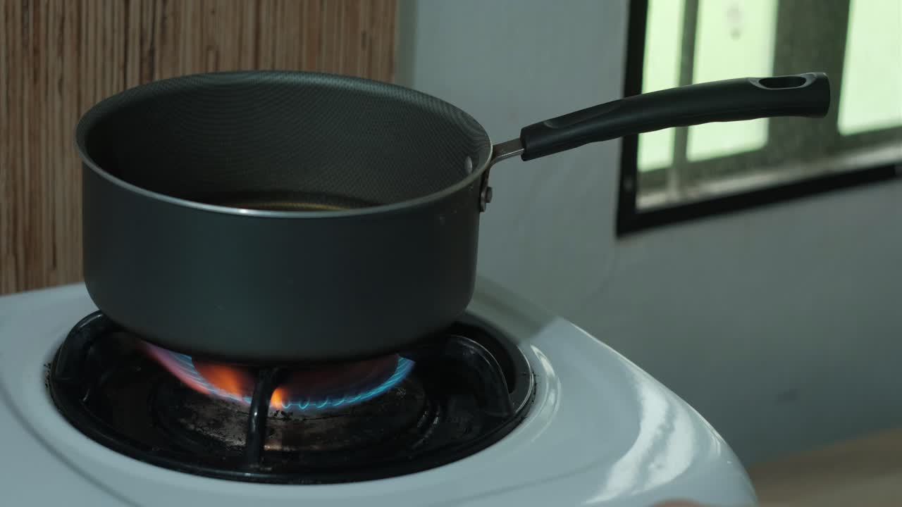 Hand placing bay leaves into a brine mixture and turning on stovetop burner. -close-up shot