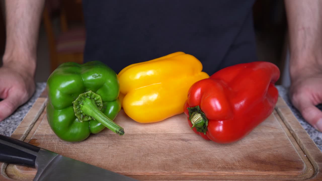pimientos rojos, verdes y amarillos sobre tabla de madera listos para cocinar